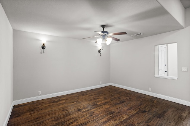 unfurnished room featuring dark wood-style floors, baseboards, visible vents, and ceiling fan