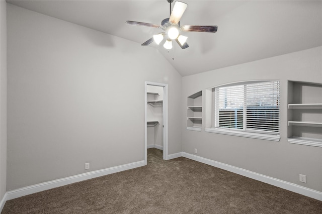 unfurnished bedroom featuring a walk in closet, carpet, baseboards, and vaulted ceiling