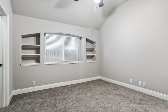 spare room with vaulted ceiling, built in shelves, carpet flooring, and baseboards