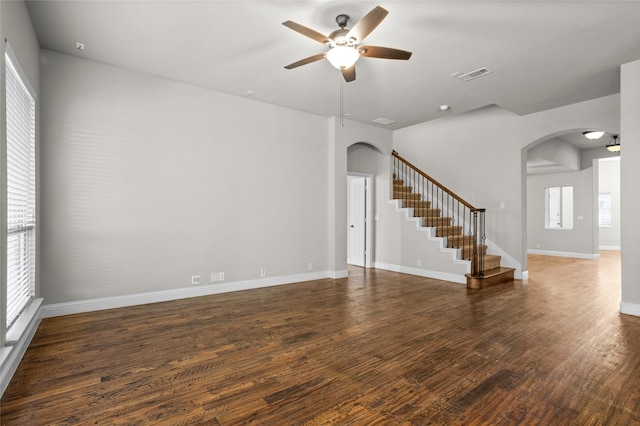 empty room with stairway, visible vents, arched walkways, and wood finished floors