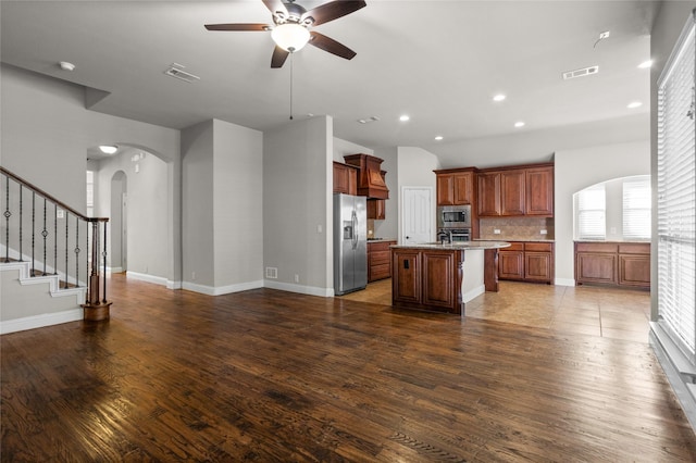 kitchen featuring arched walkways, stainless steel appliances, visible vents, open floor plan, and wood finished floors