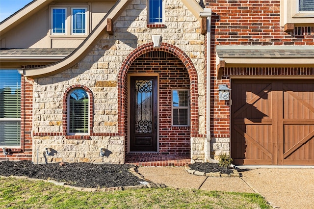 property entrance with stone siding, roof with shingles, and brick siding