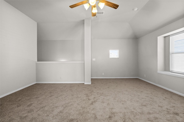 carpeted empty room featuring vaulted ceiling, visible vents, a ceiling fan, and baseboards