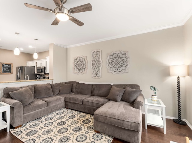 living room featuring baseboards, ornamental molding, ceiling fan, and dark wood-style flooring