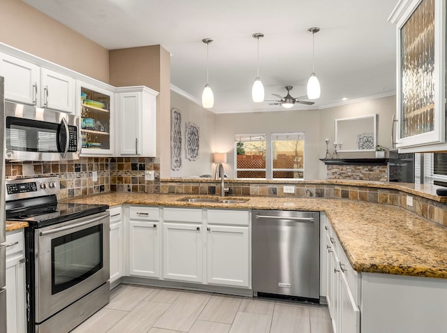 kitchen with stainless steel appliances, tasteful backsplash, white cabinetry, a sink, and light stone countertops