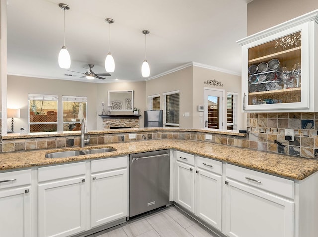 kitchen with light stone counters, a sink, backsplash, and stainless steel dishwasher