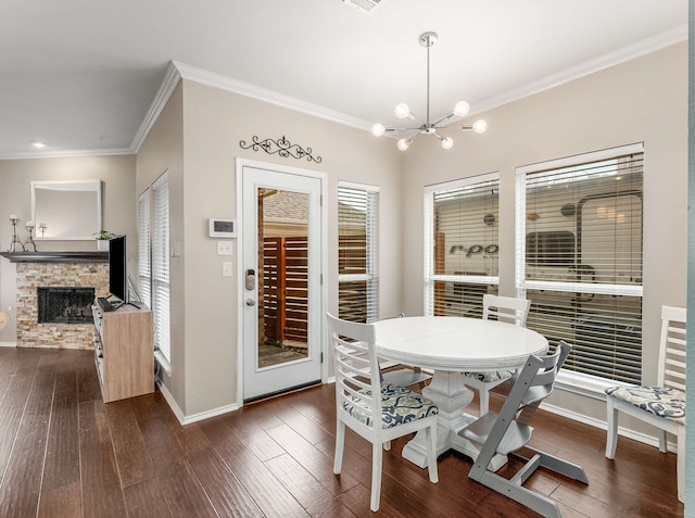 dining area with baseboards, dark wood finished floors, ornamental molding, a stone fireplace, and a chandelier