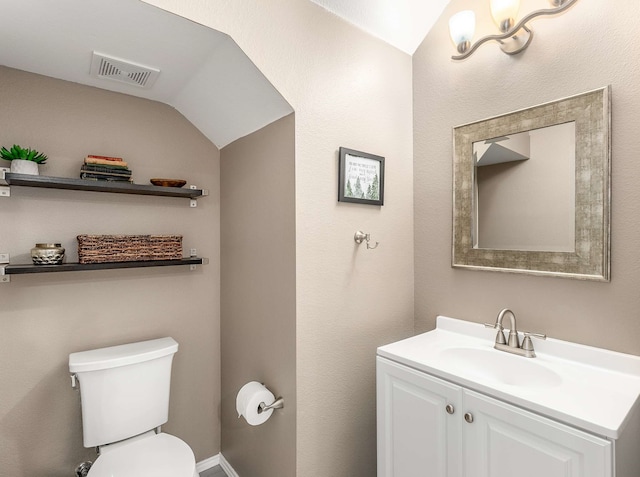 half bath with toilet, vanity, and visible vents