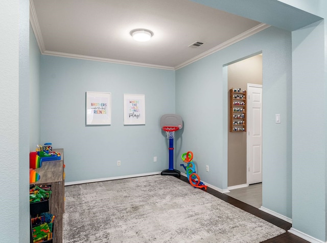 rec room featuring baseboards, visible vents, ornamental molding, and wood finished floors