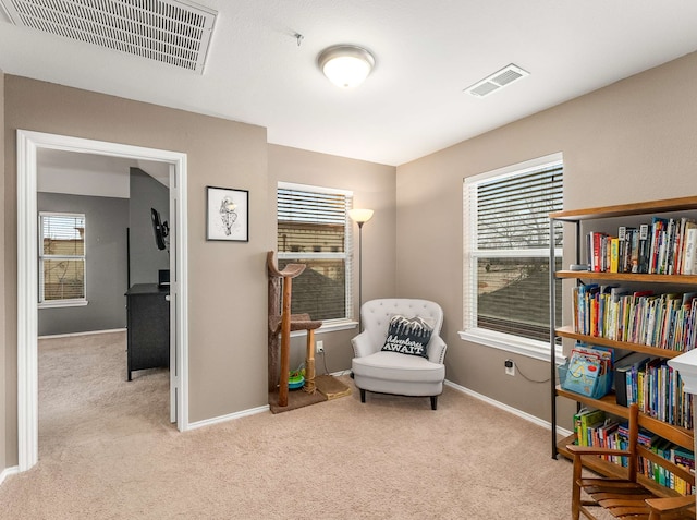 living area featuring plenty of natural light, visible vents, and light colored carpet