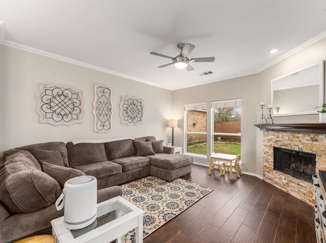 living room featuring ceiling fan, a stone fireplace, dark wood-style flooring, visible vents, and ornamental molding