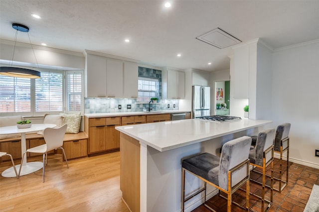 kitchen featuring crown molding, stainless steel appliances, a breakfast bar, and tasteful backsplash