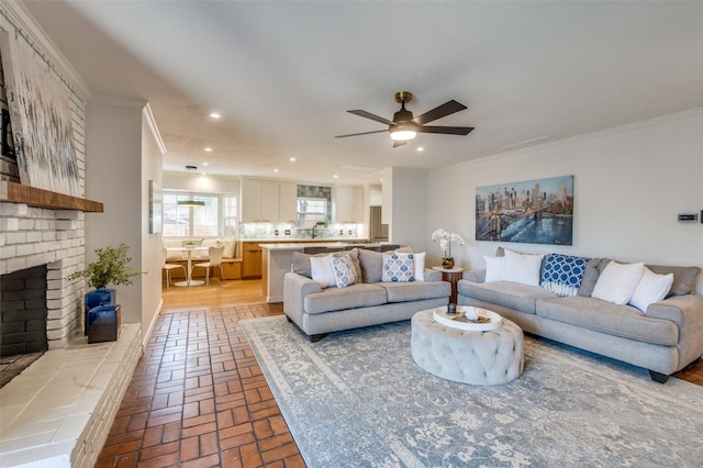 living room with brick floor, a brick fireplace, ornamental molding, and recessed lighting