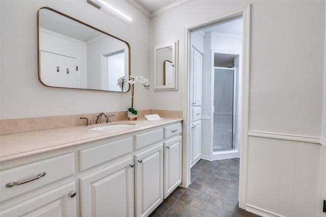 bathroom with a wainscoted wall, crown molding, a stall shower, stone finish floor, and vanity