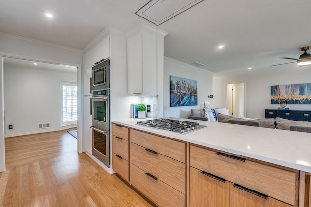 kitchen with light wood-style flooring, ornamental molding, stainless steel appliances, and open floor plan