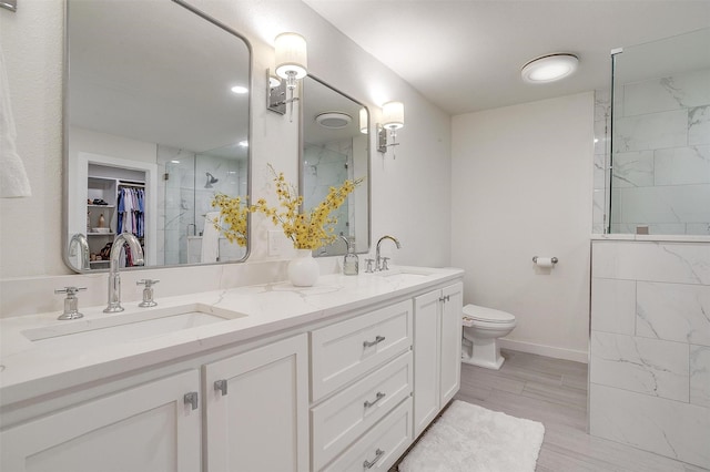 bathroom featuring a sink, a shower stall, toilet, and double vanity