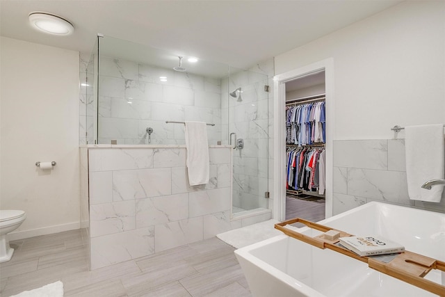 full bath with a walk in closet, toilet, a tile shower, and a freestanding bath