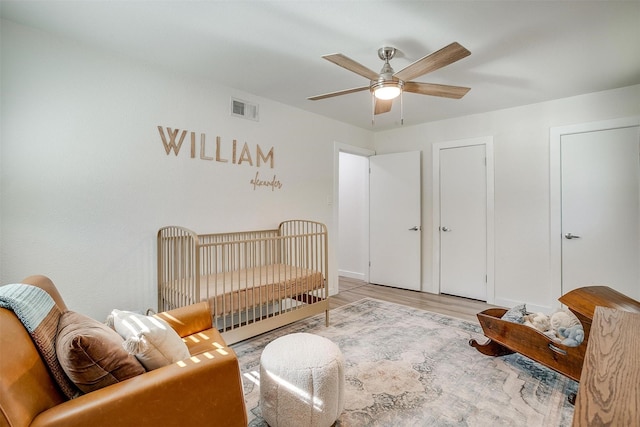 bedroom with ceiling fan, light wood-style flooring, visible vents, and baseboards