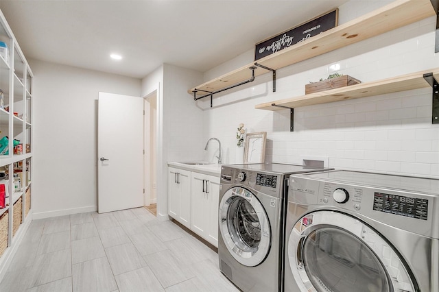 washroom with recessed lighting, a sink, baseboards, cabinet space, and washer and clothes dryer