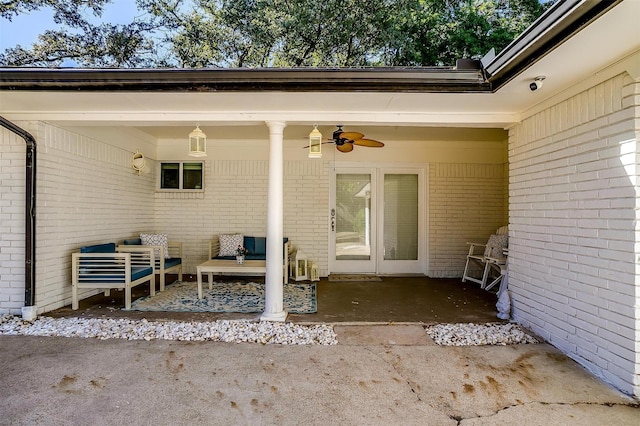 entrance to property featuring brick siding, a patio area, and a ceiling fan