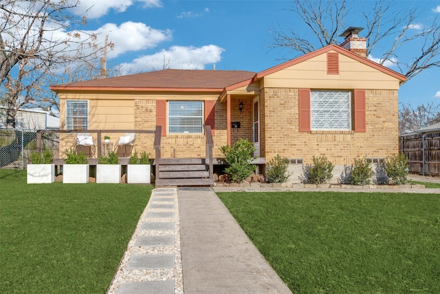 view of front of home featuring a chimney, a front yard, fence, and brick siding