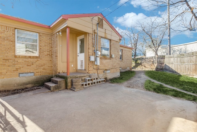 exterior space featuring brick siding, crawl space, a patio area, and fence