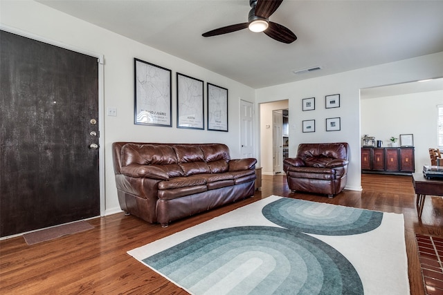 living room with a ceiling fan, visible vents, and wood finished floors