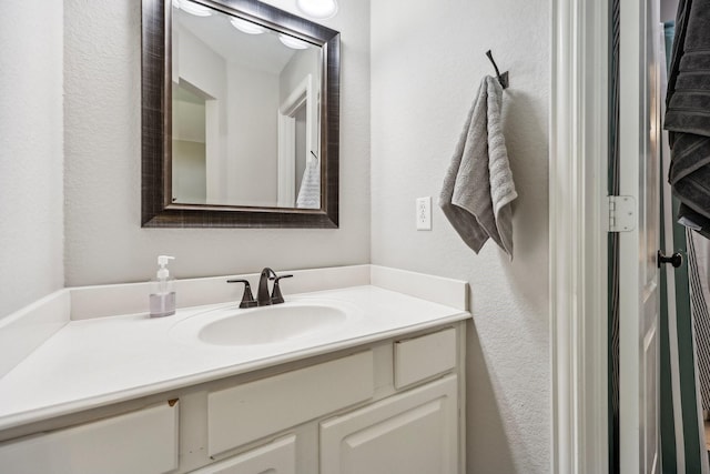 bathroom with a textured wall and vanity