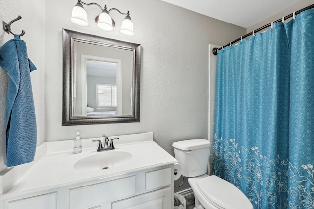 bathroom featuring a textured wall, curtained shower, vanity, and toilet