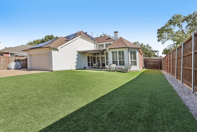 back of house featuring a garage, a lawn, a fenced backyard, a patio area, and roof mounted solar panels