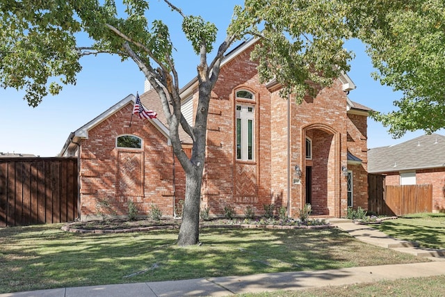 view of front of home with brick siding, fence, and a front lawn