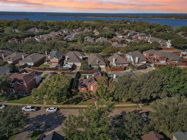 aerial view at dusk with a water view and a residential view