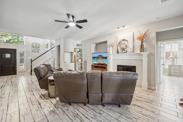 living room with visible vents, ceiling fan, wood finished floors, stairs, and a fireplace