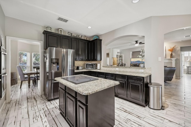 kitchen featuring visible vents, decorative backsplash, appliances with stainless steel finishes, a center island, and a healthy amount of sunlight