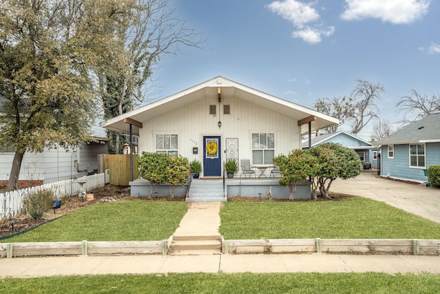 bungalow-style house featuring driveway, a porch, a front yard, and fence