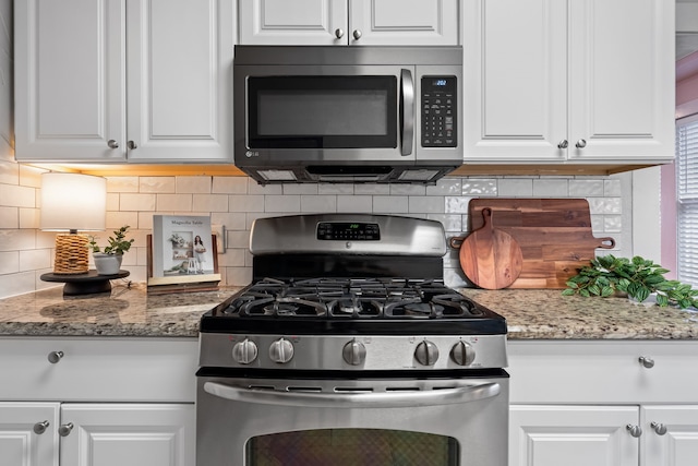 kitchen featuring light stone counters, white cabinetry, stainless steel appliances, and backsplash