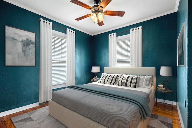 bedroom featuring a ceiling fan, crown molding, baseboards, and wood finished floors