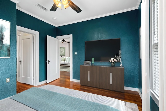 bedroom with dark wood-style floors, visible vents, a textured wall, ornamental molding, and baseboards