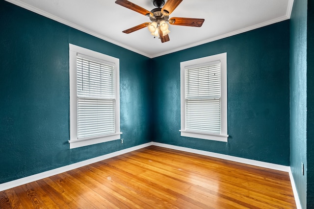 spare room with baseboards, a textured wall, wood finished floors, and crown molding