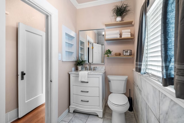 bathroom featuring marble finish floor, toilet, ornamental molding, vanity, and baseboards