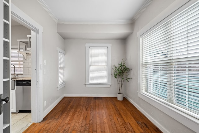 spare room featuring light wood finished floors, baseboards, ornamental molding, and a sink