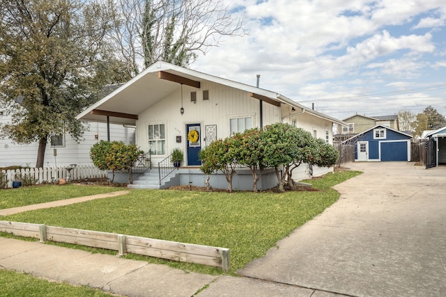 view of front of home featuring an outdoor structure, concrete driveway, and a front yard