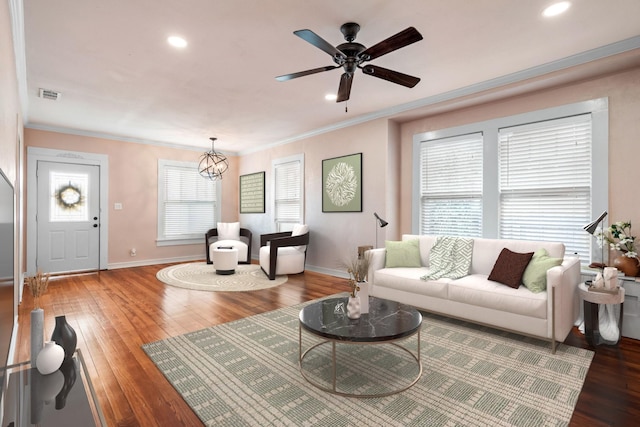 living area featuring wood-type flooring, visible vents, and crown molding