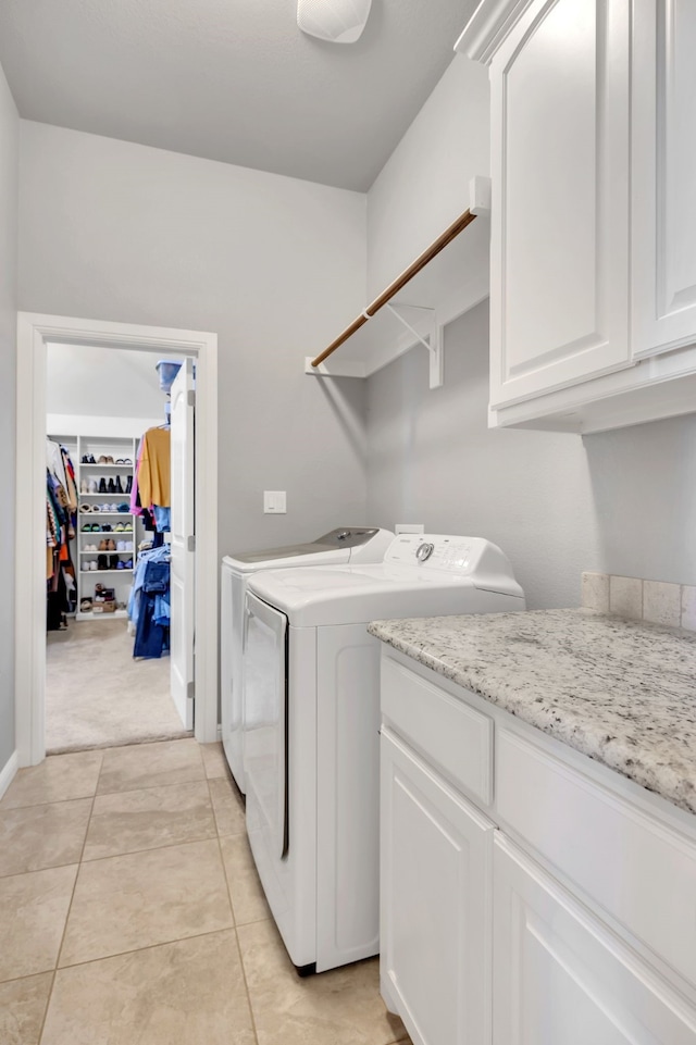 laundry room featuring light tile patterned floors, washing machine and clothes dryer, and cabinet space