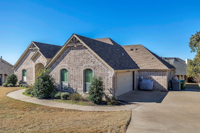 french country home featuring central AC unit, a garage, brick siding, a shingled roof, and concrete driveway