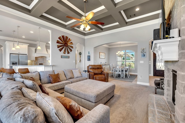 living area with light carpet, visible vents, arched walkways, coffered ceiling, and crown molding