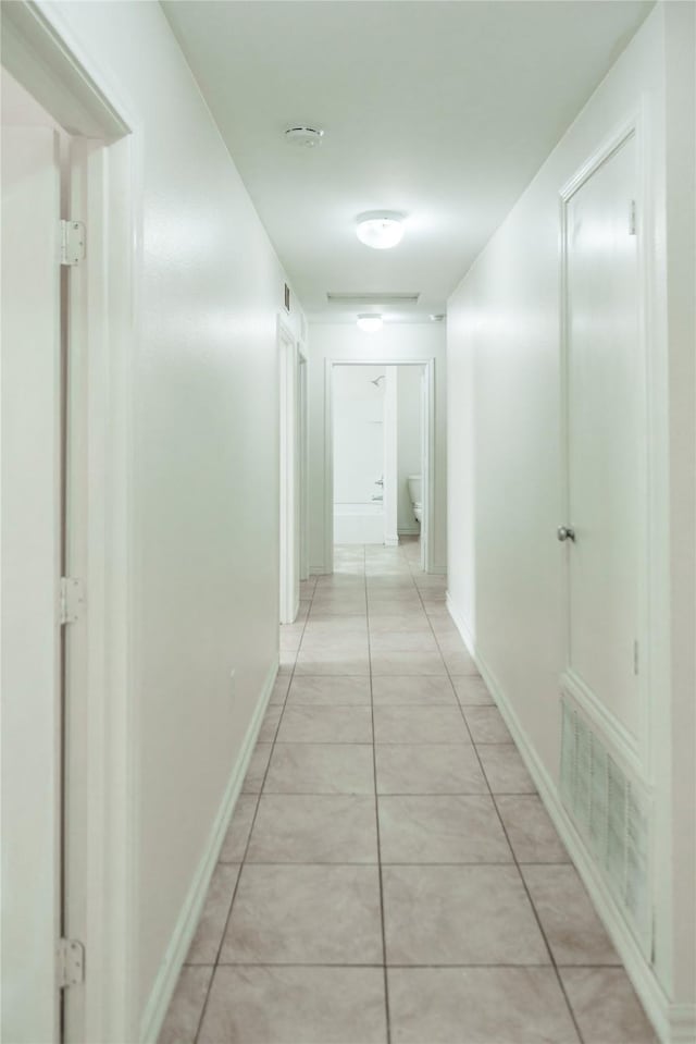 corridor with light tile patterned floors, baseboards, and visible vents