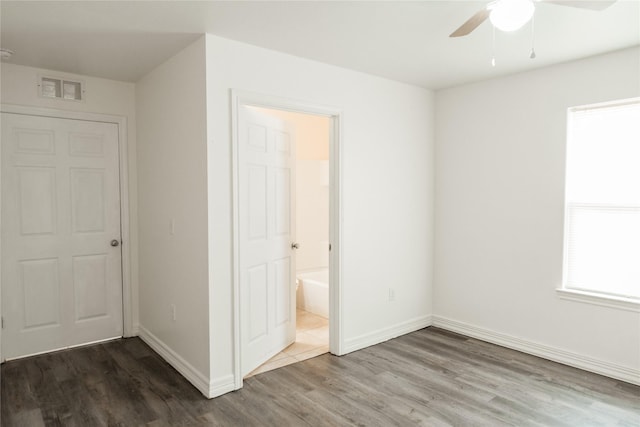 unfurnished bedroom featuring ceiling fan, connected bathroom, wood finished floors, visible vents, and baseboards