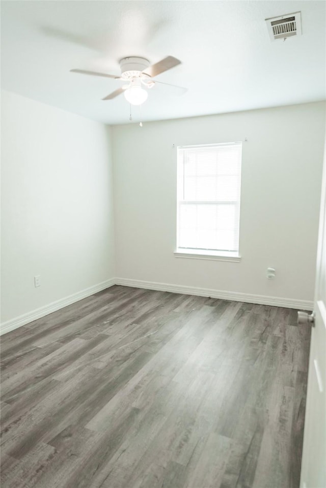 empty room featuring ceiling fan, wood finished floors, visible vents, and baseboards