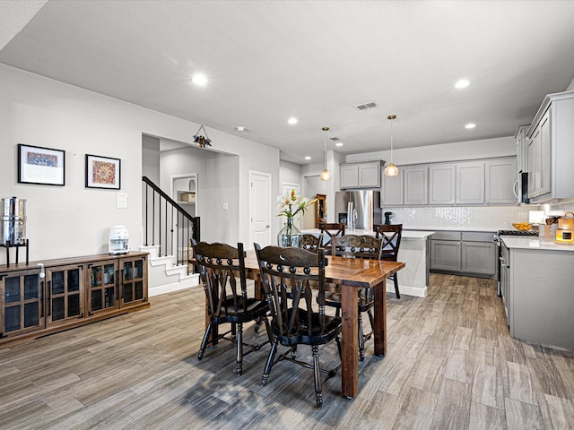 dining room featuring light wood-style floors, recessed lighting, visible vents, and stairway